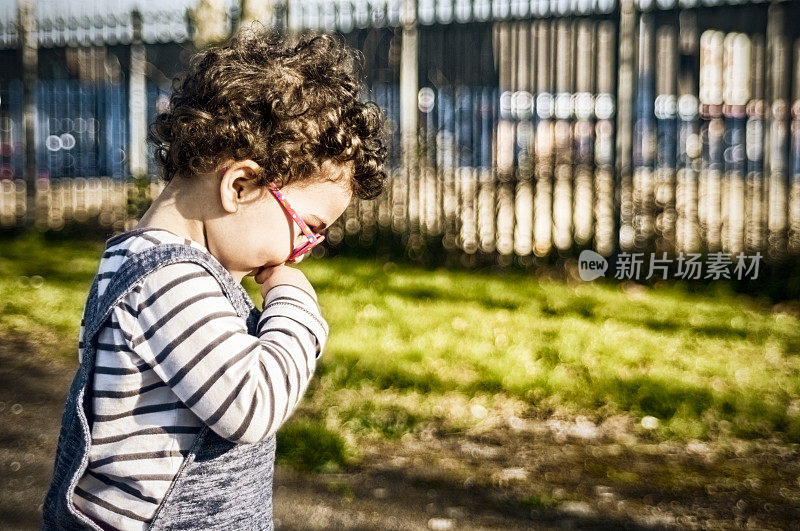 人物:幼儿(2-3)的侧视图，手指在嘴里。