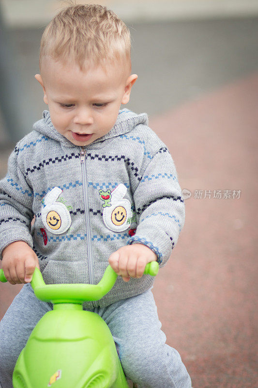骑着塑料滑板车的小男孩