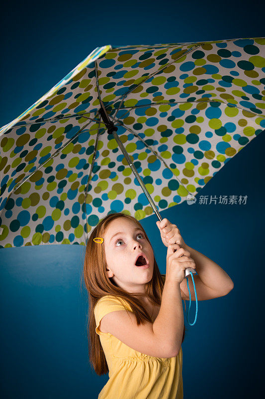 惊讶的七岁红发女孩拿着伞