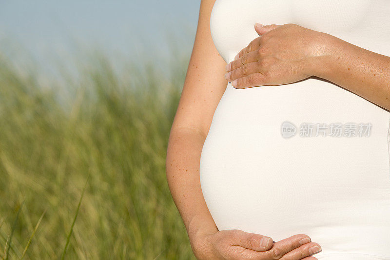 一个孕妇双手放在肚子上