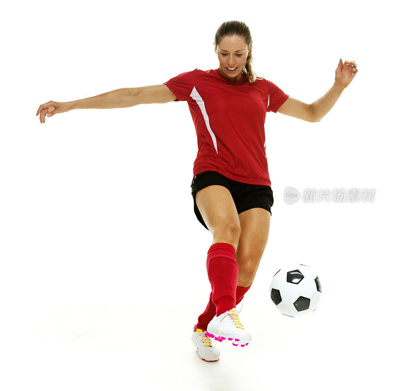 微笑的女足球运动员踢着球