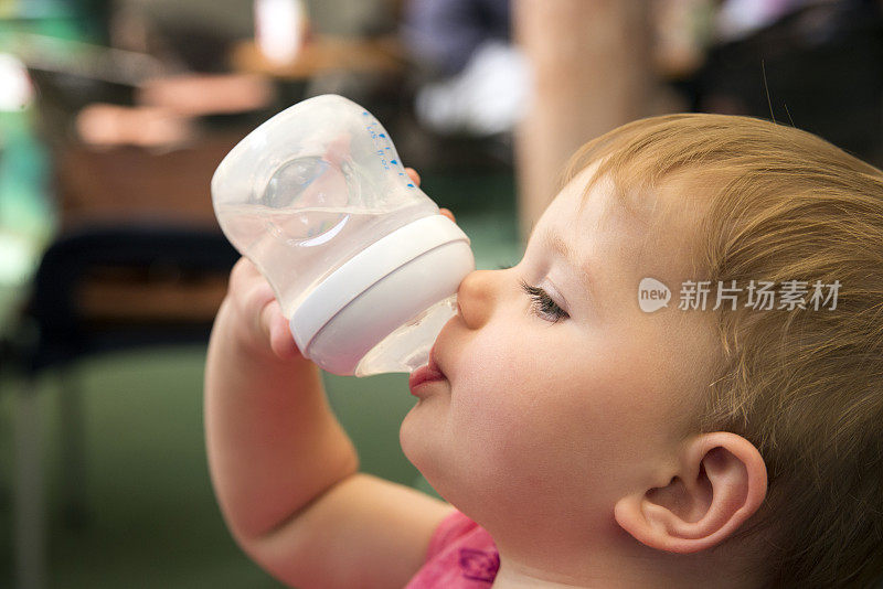 可爱的孩子从瓶子里喝水