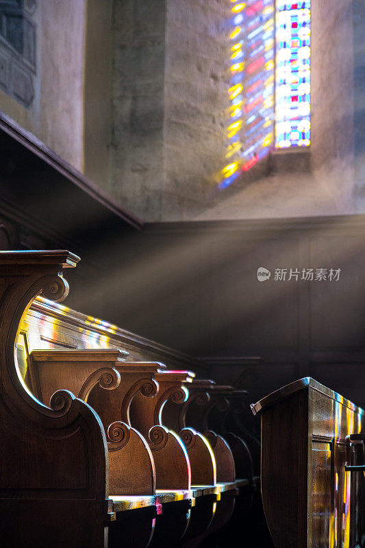 透过彩色彩色玻璃的阳光照亮了教堂里的木制摊位