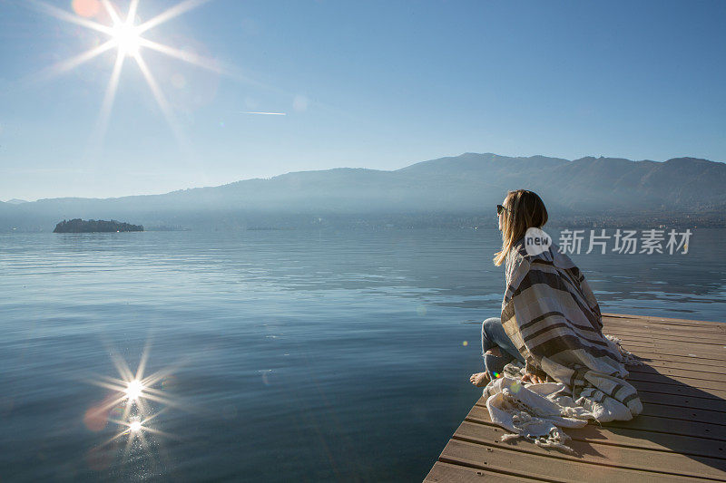 年轻女子在湖边码头上休息，看风景