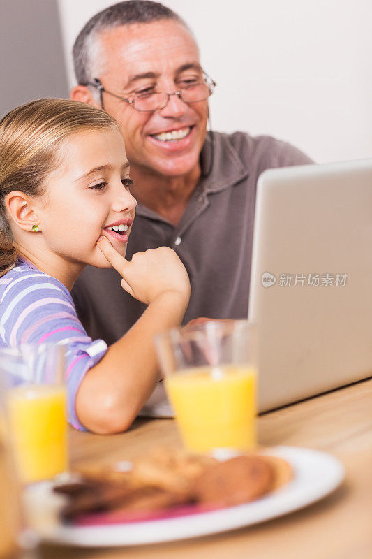 女孩和爷爷一起看笔记本电脑
