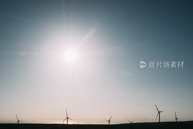 风力涡轮机对着晴朗的天空和太阳耀斑。