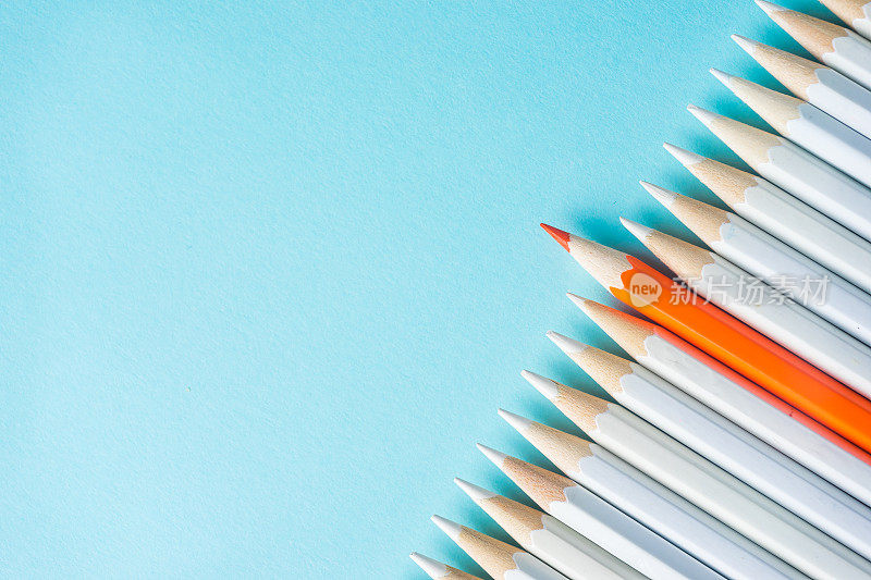许多白色铅笔和彩色铅笔在蓝色纸的背景。