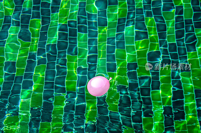 绿色游泳池的表面，游泳池的水的背景。游泳池里有气球。