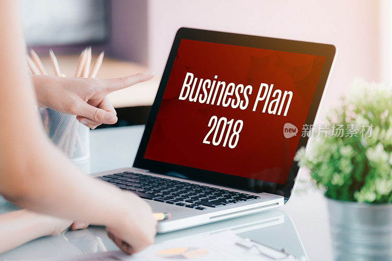 商务人士在笔记本电脑屏幕前开会，在办公室桌上写着2018年商业计划，数字营销概念。