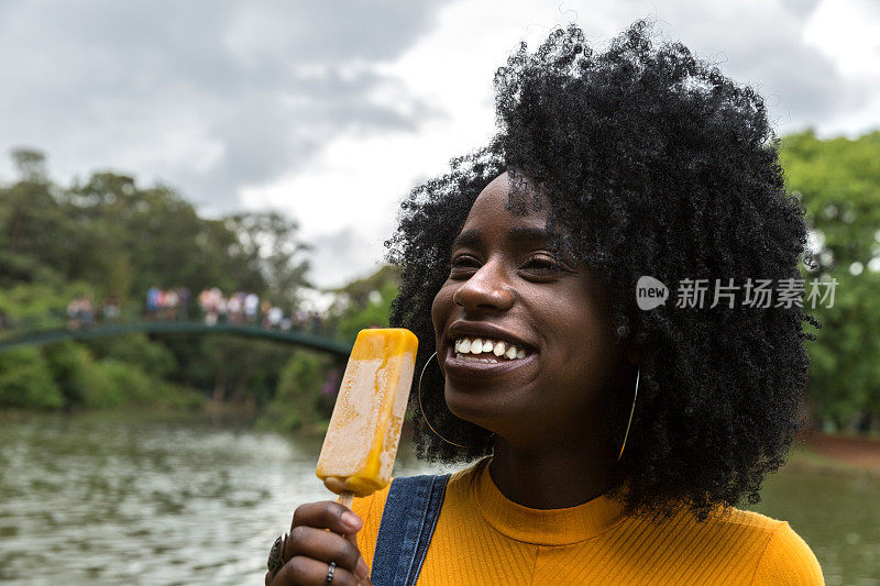 非洲女孩享受有趣的冰淇淋在公园笑，笑在暑假的快乐