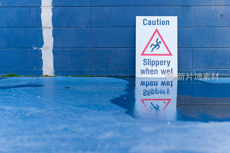 当湿的标志反映在水坑时，小心滑