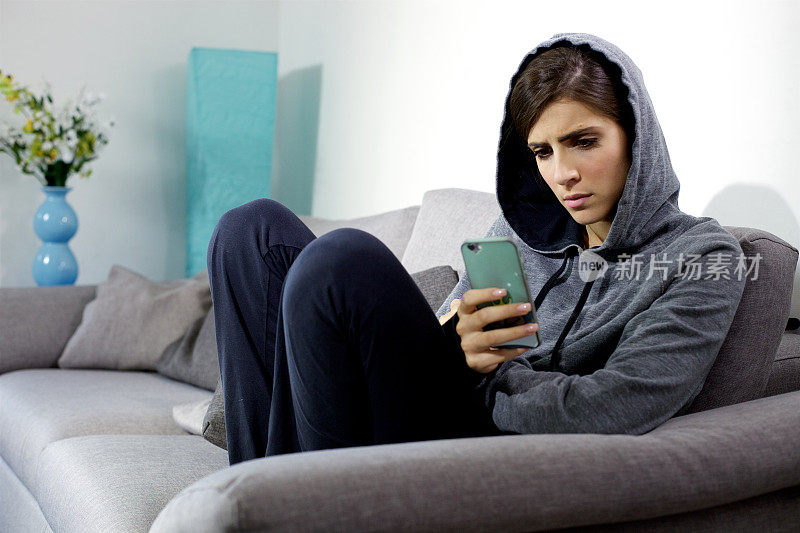 女人在家看手机担心负面评论在社交媒体上广泛拍摄
