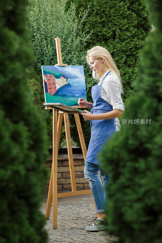一名女艺术家手持画笔在画布上作画