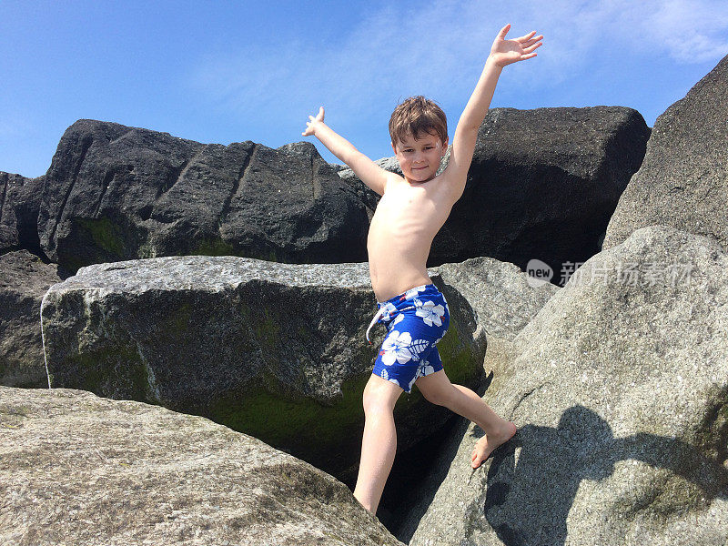 一个六岁的男孩在沙滩上玩石头