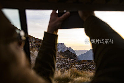 成年男子用手机从汽车上拍摄山景