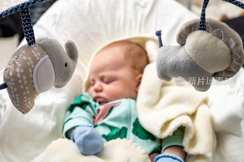 婴儿玩具在前景与婴儿睡觉在婴儿秋千近距离