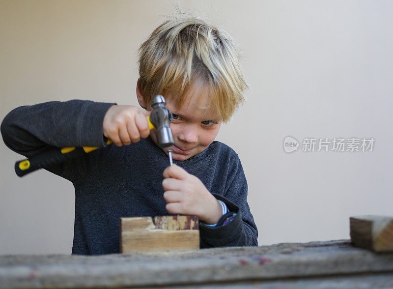 一个和木工工具一起工作的小男孩