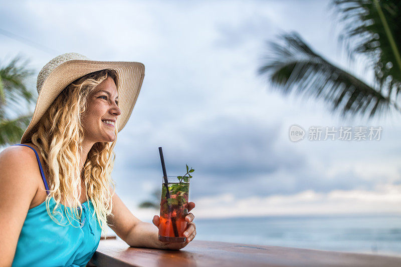 快乐的女人在海滩酒吧享受夏日鸡尾酒。