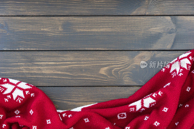 黑色的木制背景上是皱巴巴的雪花编织的传统圣诞图案红毯。