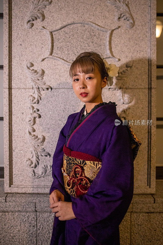 年轻女子的肖像在“Furisode”和服站在白色墙壁在晚上