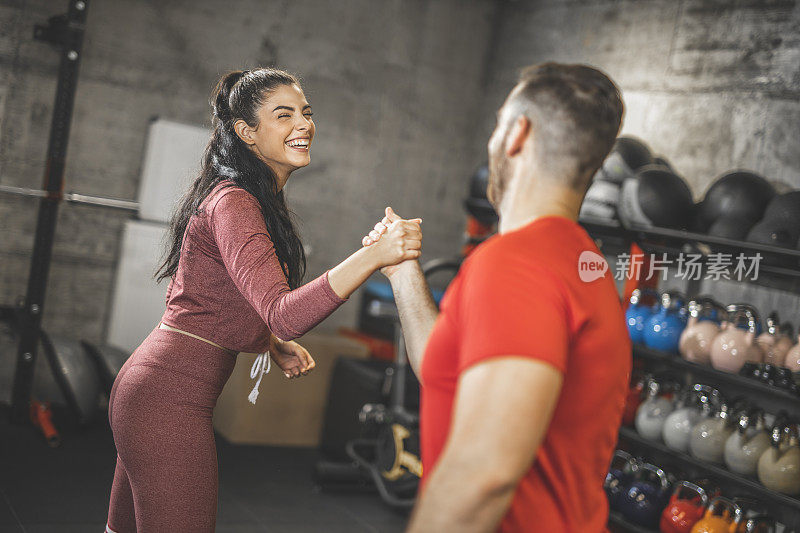 年轻的女人和男人在体育馆的高强度训练后正在握手