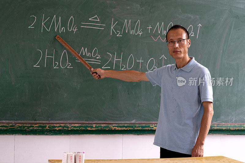一位亚洲中年男教师在黑板前解释