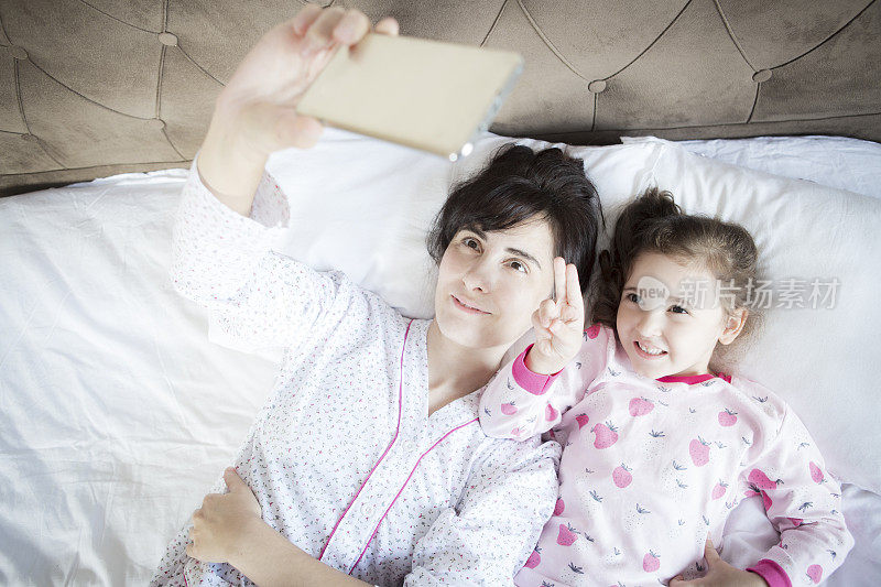 年轻家庭在床上用智能手机自拍