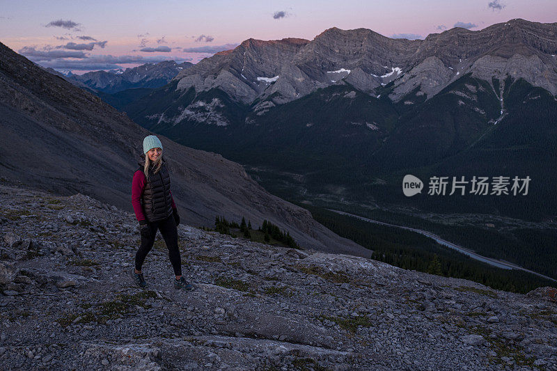 女人在日出时沿着山脊徒步