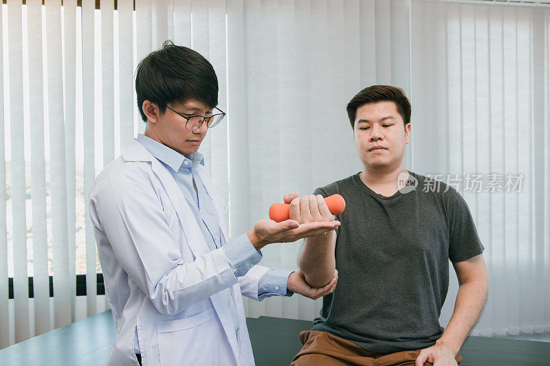亚洲的理疗师正在帮助病人举起哑铃来恢复手臂。