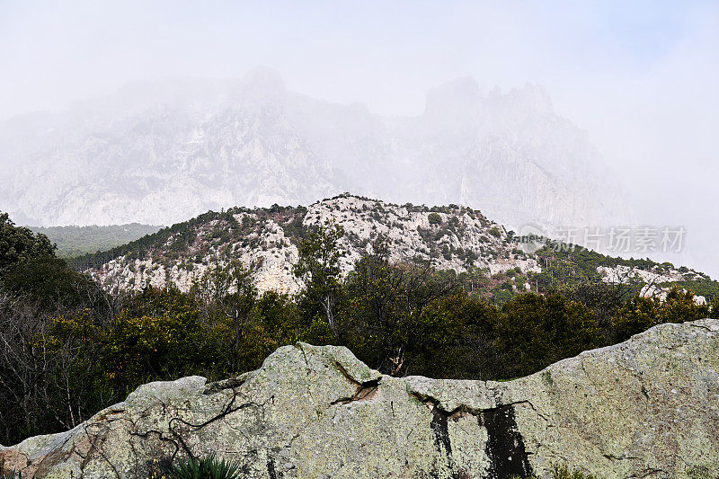 雾中的山脉在前景的岩石后面几乎看不见