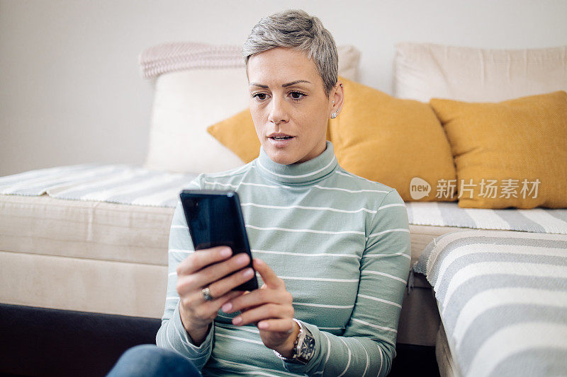 一个在家用智能手机发短信的女人的肖像