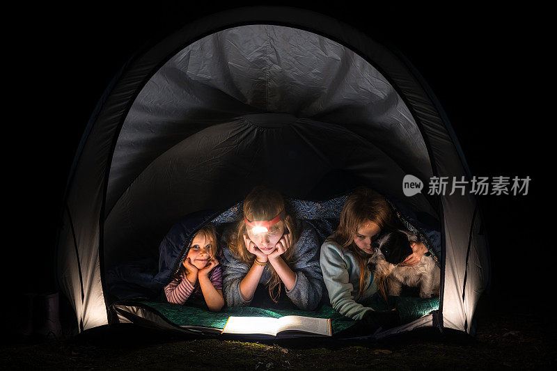 孩子们晚上在露营帐篷里用手电筒看书