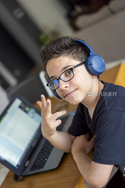 十几岁的男孩是唱歌与他的手指树家庭学校在笔记本电脑从家庭学校和远程学习