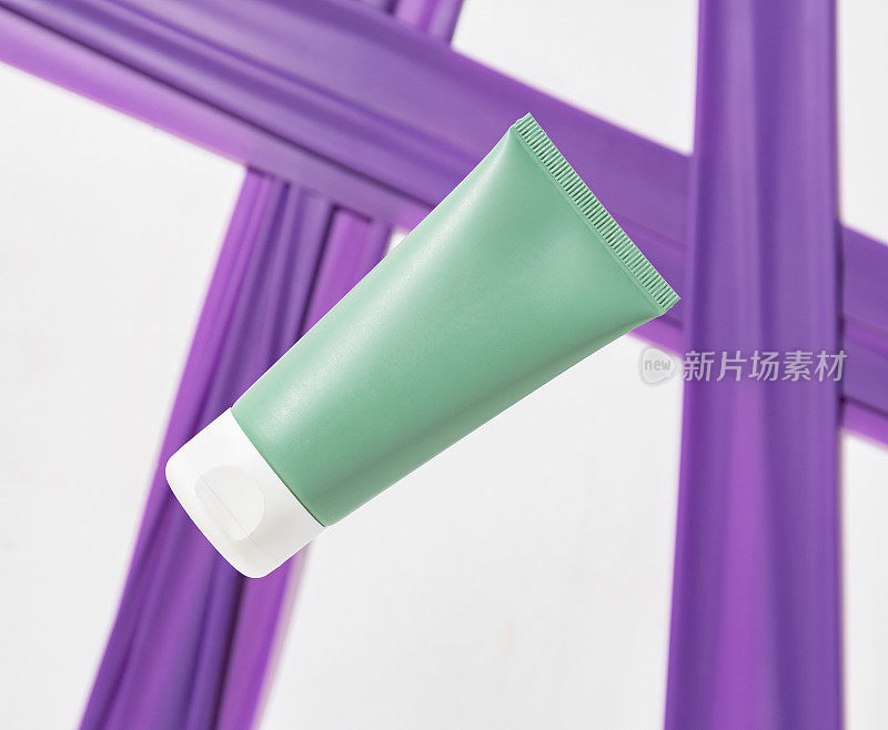 绿色塑料管在白色和紫色的背景。护肤护发产品