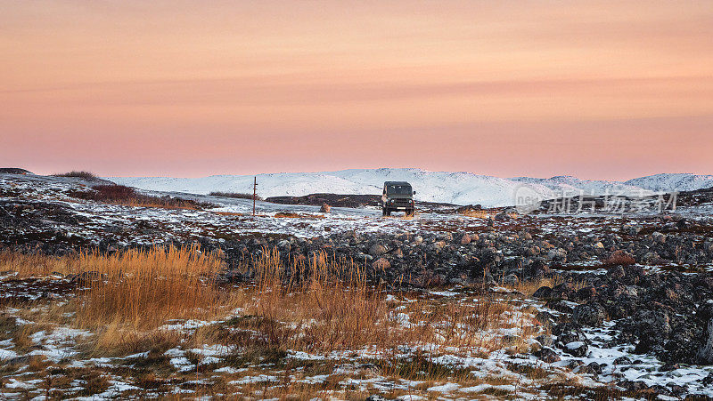 游客乘车降落的全景。穿过苔原的冰冷而滑的北极道路。