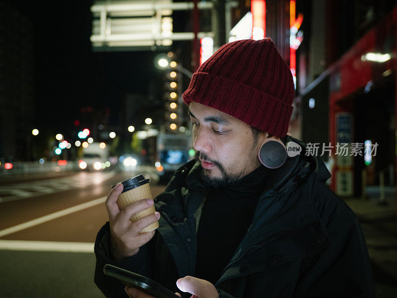 年轻的亚洲男子在东京等出租车或优步在晚上。