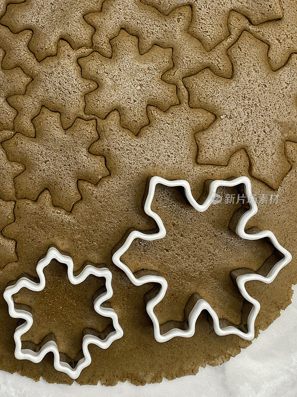 全框图像自制，姜饼曲奇面团滚在防油的羊皮纸上与大小塑料雪花形状的饼干切刀，雪花切割形状，家庭烘焙，高架视图