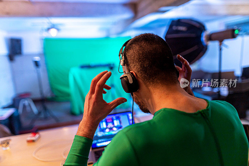 无法辨认的DJ，穿着绿色的西装，在录音棚用笔记本电脑工作