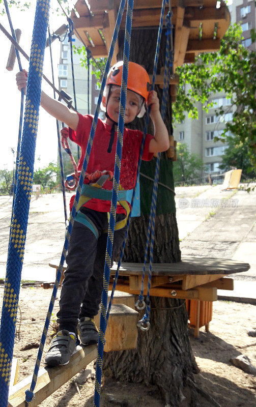 一个小男孩在绳索公园穿过一座吊桥