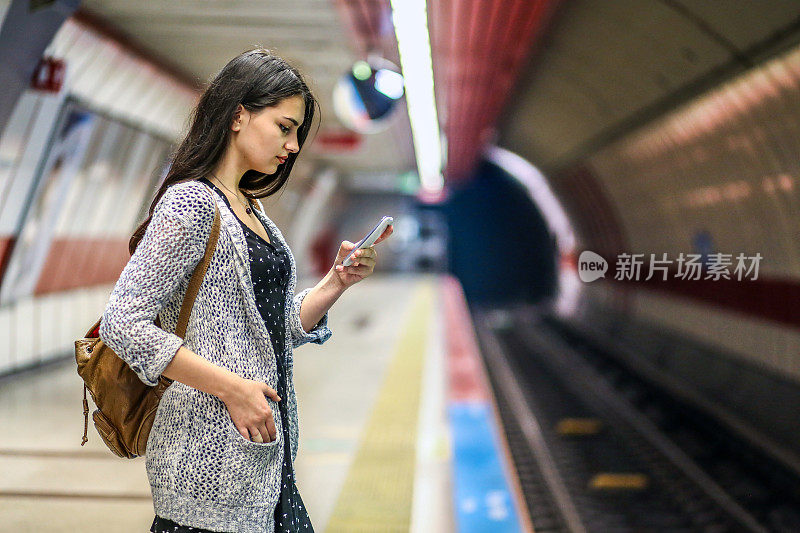 年轻女人看电话，乘客在车站等地铁，旅游女人在城市旅行