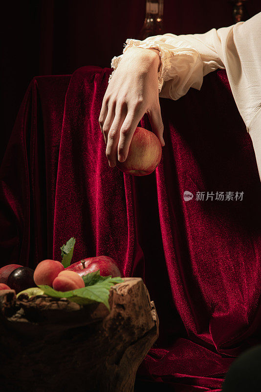 特写男性的手与红苹果在黑暗的vintage背景。意大利巴洛克风格，艺术，创意，复古