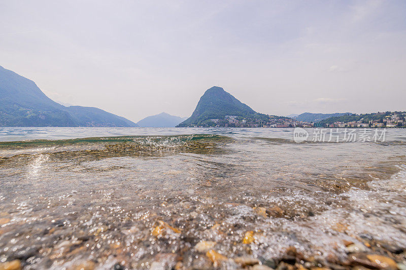 卢加诺湖岸的水在群山和天空的映衬下流淌的美丽景色