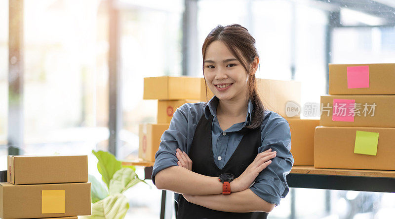 年轻有吸引力的亚洲女性业主创业看相机工作快乐与盒子在家里准备中小企业供应链包裹交货
