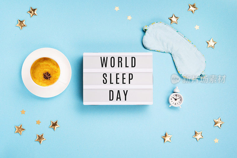 睡眠面具，姜黄金色牛奶拿铁和闹钟在蓝色背景。世界睡眠日概念。