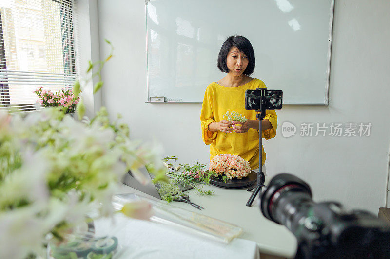 亚洲女花艺老师，小型企业花艺课程的老板，在线教授插花课程，使用智能手机，相机和笔记本电脑进行视频记录。电子学习，在线教程的概念