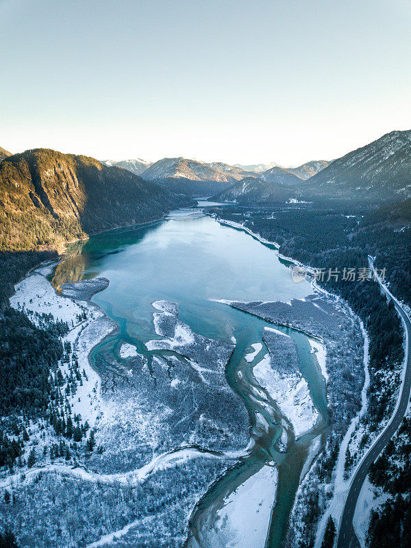 德国巴伐利亚州Sylvensteinsee冬季鸟瞰图。这个冰冻的湖泊部分被冰雪覆盖，而无人机拍摄到的其他地方可以看到清澈的蓝色湖水