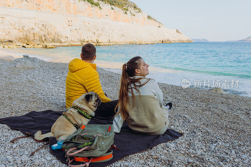 幸福的夫妇和狗在土耳其的海滩上沉思春天