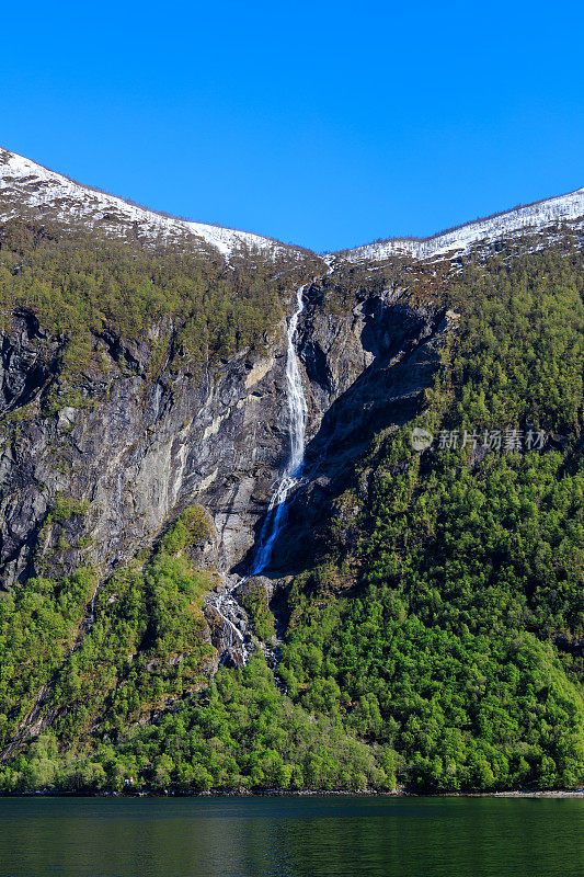 从Geirangerfjord乘船欣赏雪山、树木、瀑布和晴朗的天空