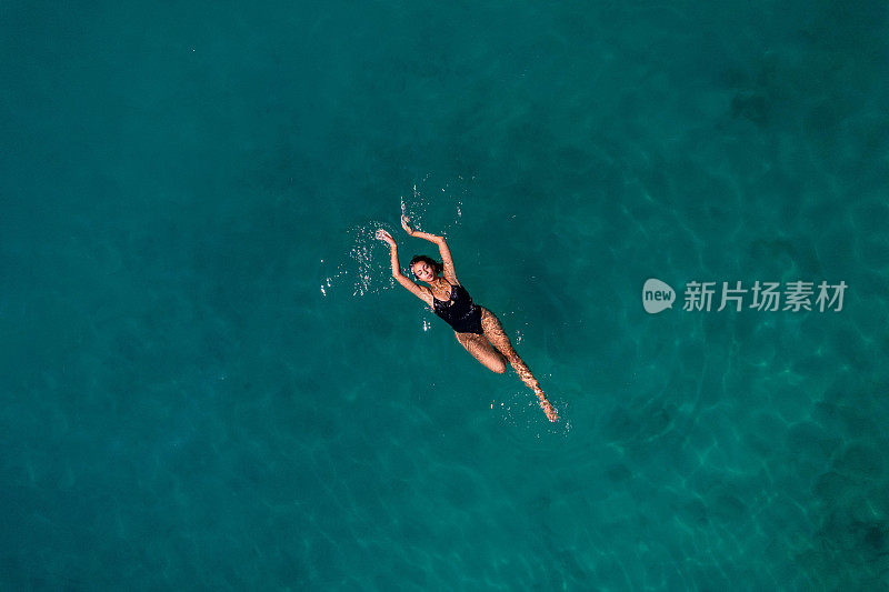 年轻女子漂浮在深蓝色的大海上