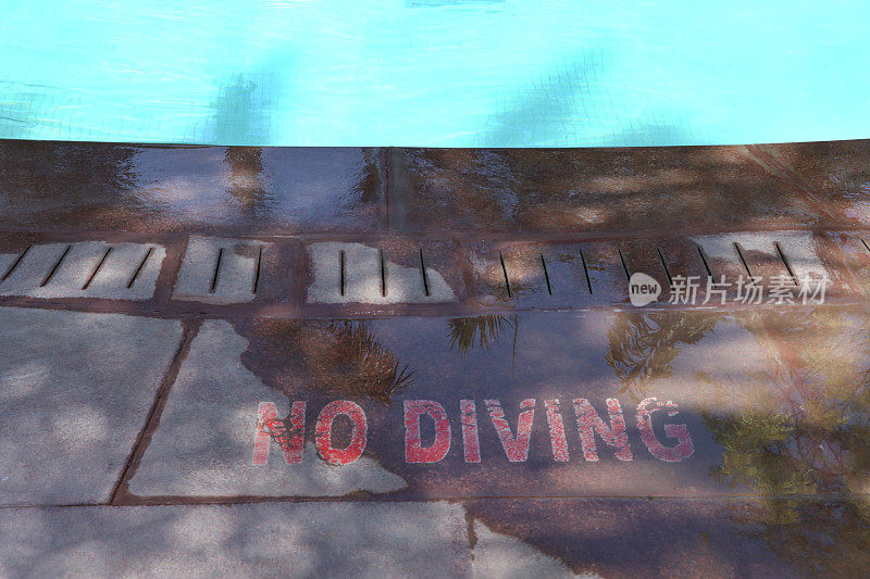室外特写，游泳池碧蓝的马赛克瓷砖被荡漾的水扭曲，泳池边的石头露台方板上画着禁止潜水的警告标志，溅起的水，高架的景色